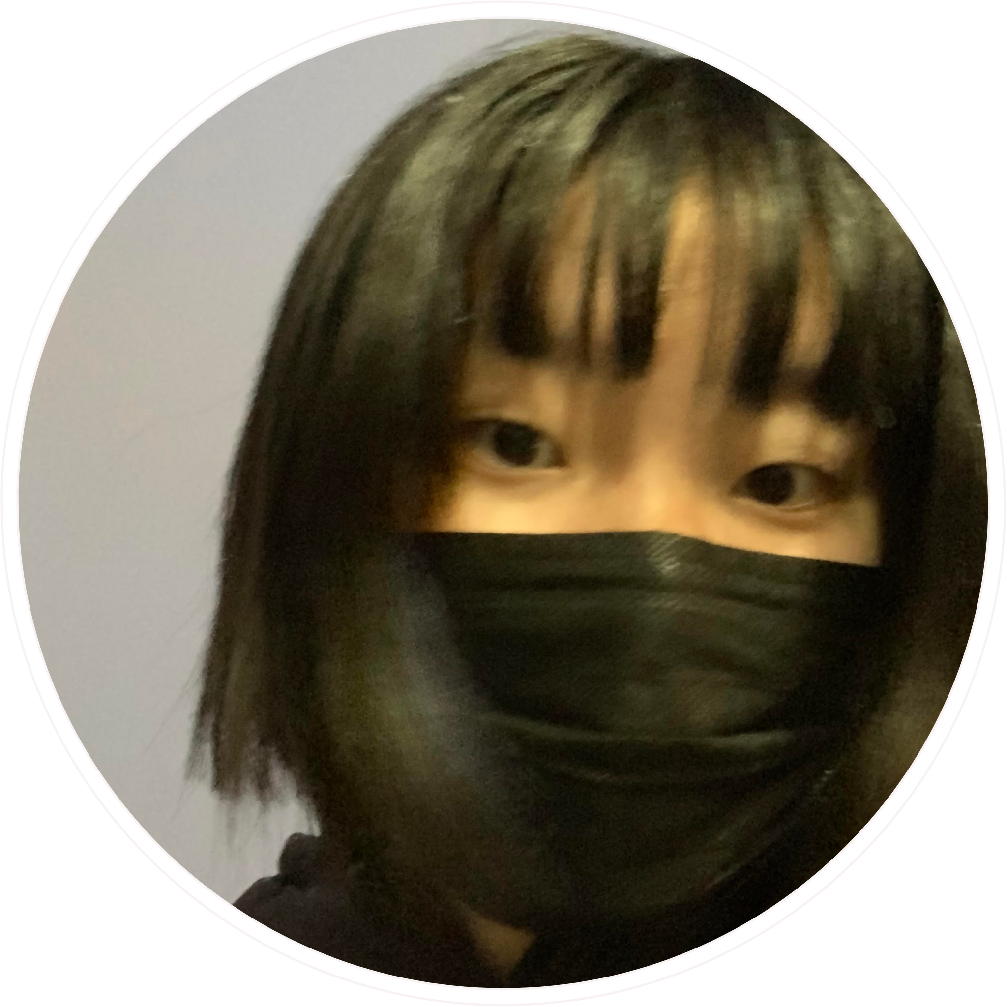 Girl with short, black hair wearing a mask against a gray background