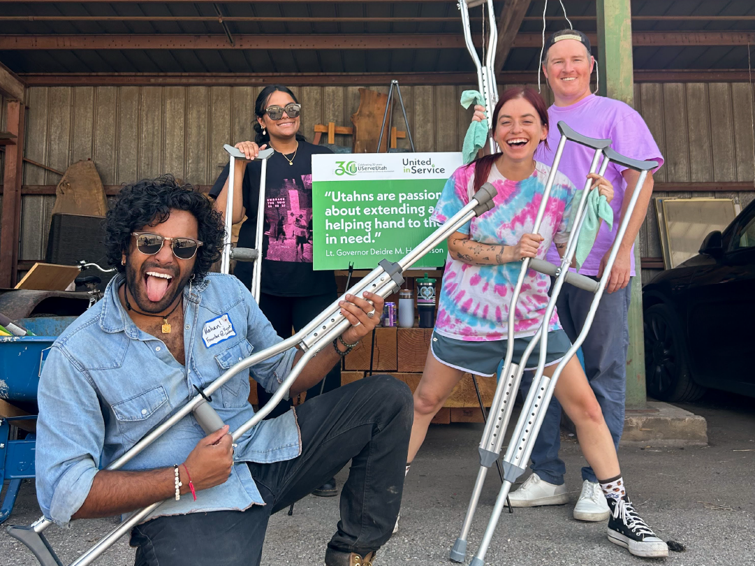 Volunteers at a service project posing with crutches in front of a UServeUtah sign