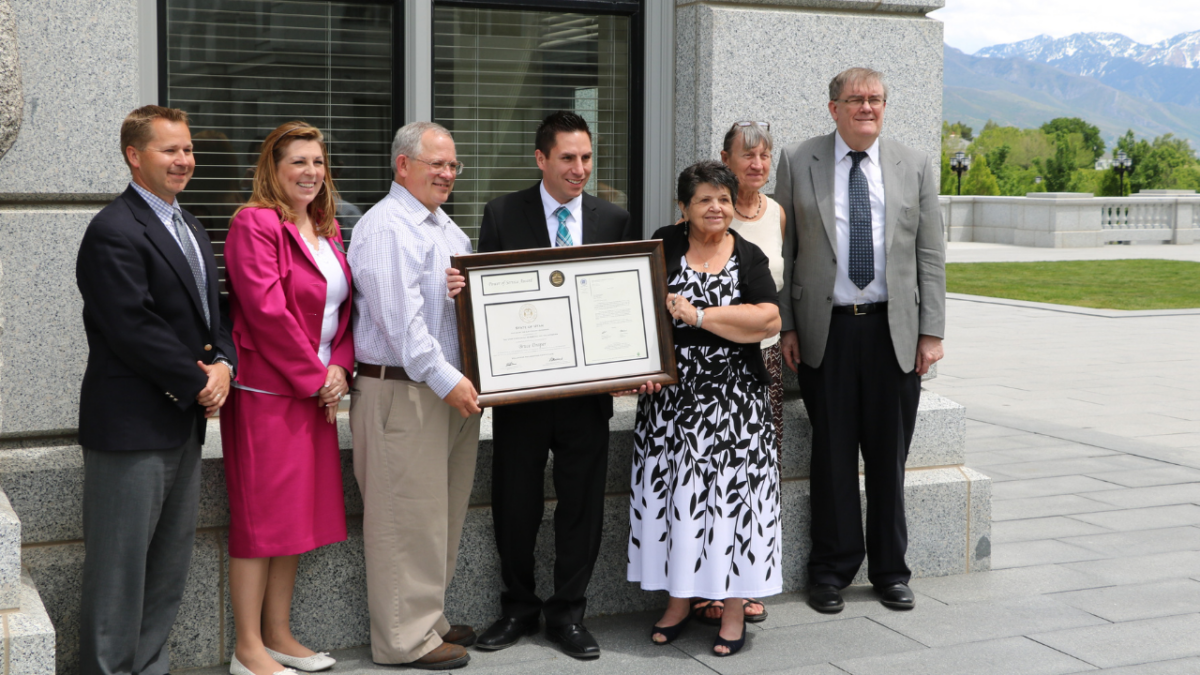 Individuals outside Utah Capitol holding large framed award.