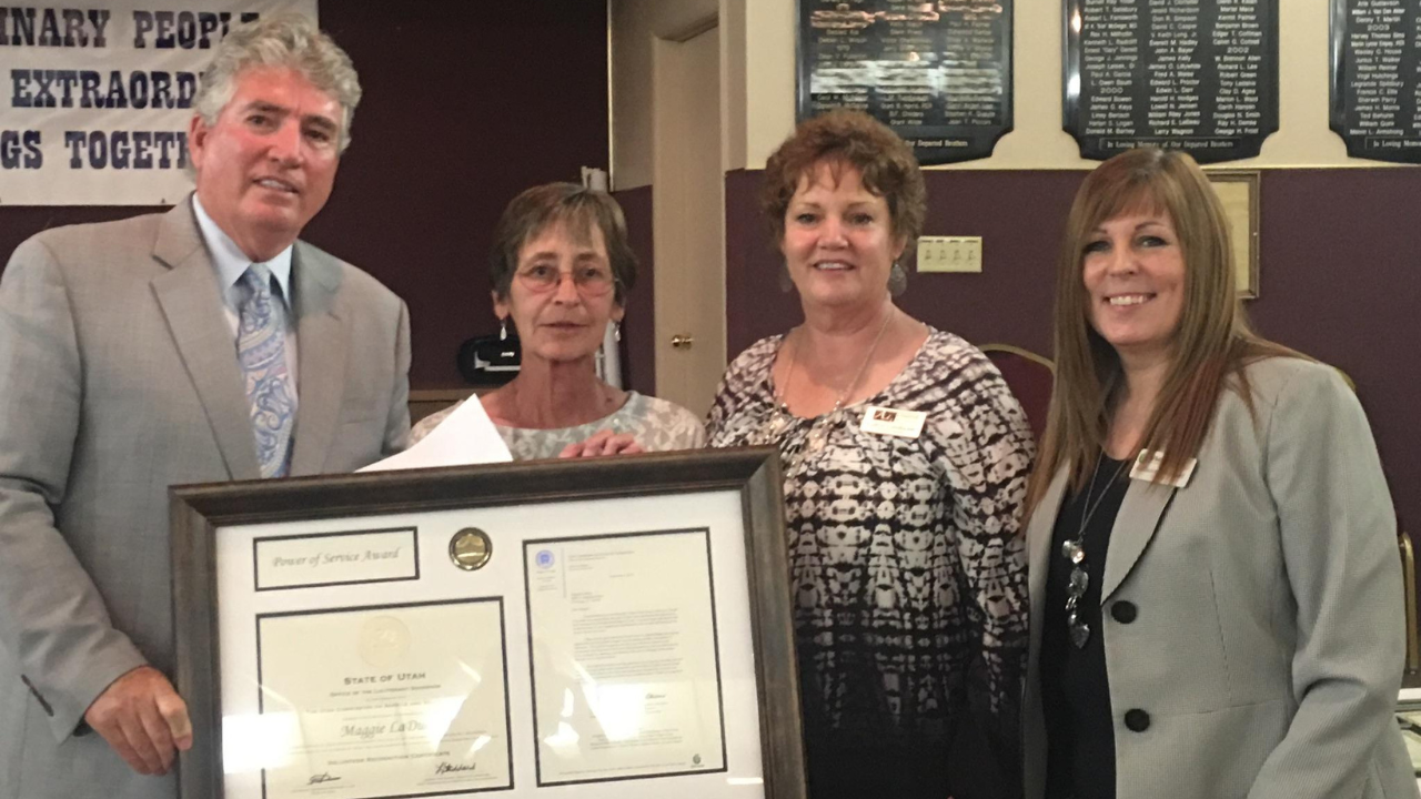 Individuals standing holding large framed award.