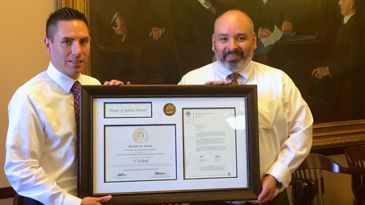 Two men holding large framed award.