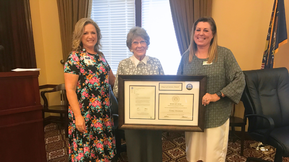 Debbie Hardy, Norma Paramore, and LaDawn Stoddard standing in Capitol Board Room holding large framed award.