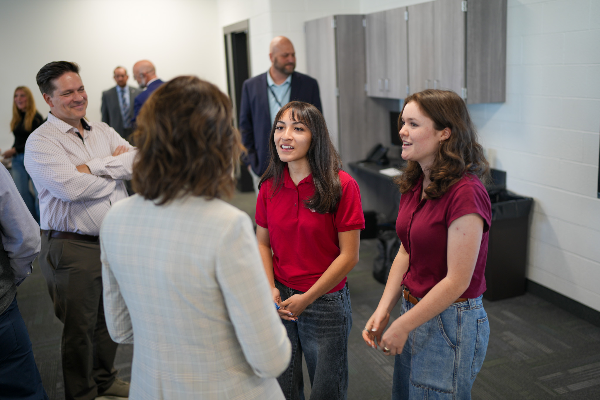Lt. Governor henderson speaking with two high school students wearing red shirts