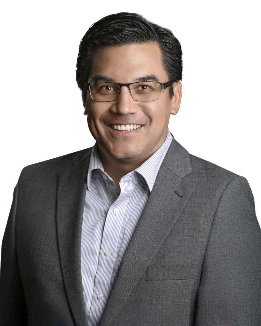Man with short black hair and glasses smiles at camera wearing striped polo shirt and gray blazer in front of white background