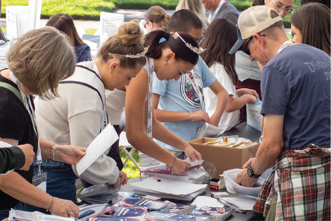Group of community members in an outdoor setting assembling kits at a service project