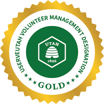 Gold badge with Utah beehive emblem and text: Volunteer Management Designation Gold.