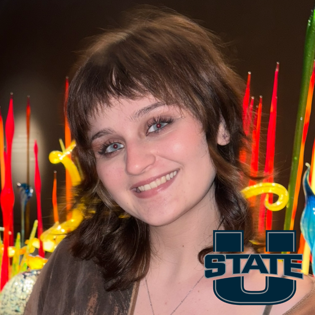 CCEC member Amy Adams a smiling woman with shoulder length brown hair, black long sleeve top in an outdoor setting. Include's Southern Utah University's "SUU" logo with thunderbird icon.